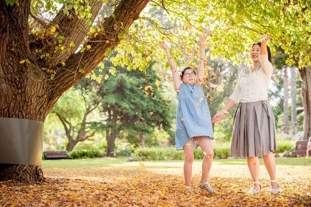 Mother And Daughter Throwing Leaves At Williamstown Botanic Gardens